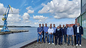 Die Gruppe steht auf der Dachterasse vor dem Konferenzraum des TZF. Über ihr ist ein wunderschöner Himmel mit Wolken zu sehen.